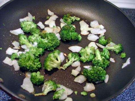 Broccoli and onions being sauteed in a pan